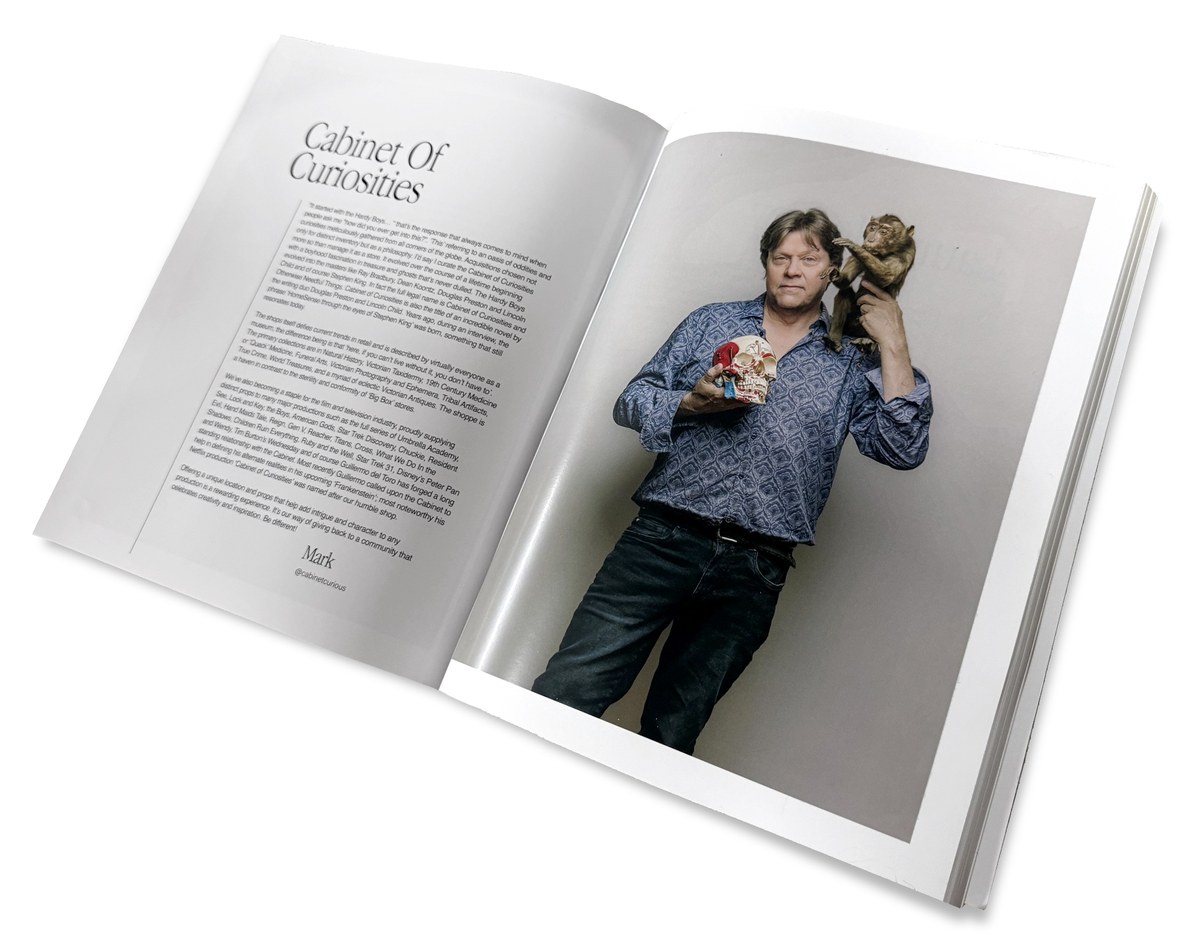 Mark Draak photographed for the book Home Made Hamilton, holding a piece from the collection, beside a two-page spread about the Cabinet of Curiosities